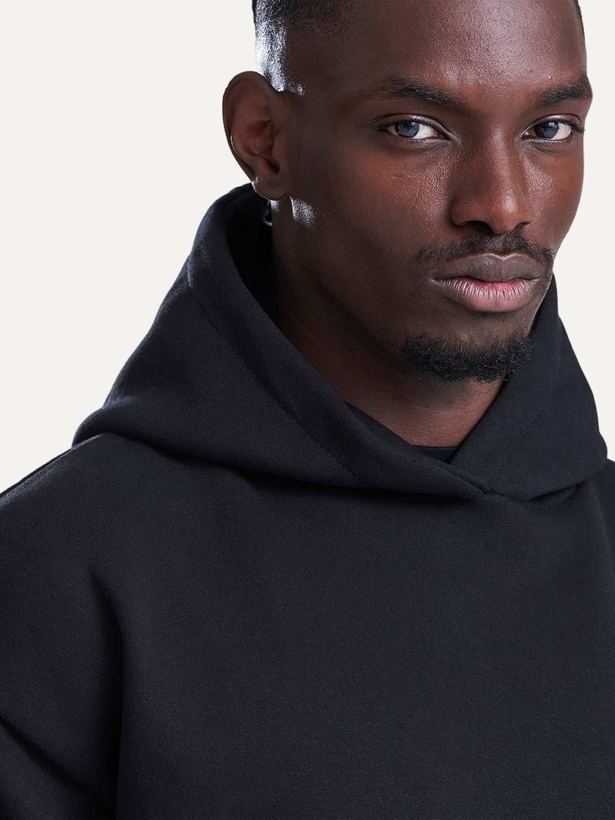 Close-up of the Essential Hoodie hood in Deep Black, worn by a model